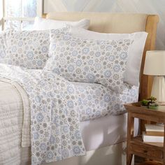 a bed with white and blue comforters in a bedroom next to a night stand