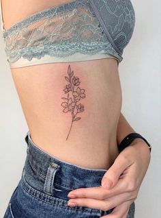 a woman's stomach with a small flower tattoo on her side ribcage