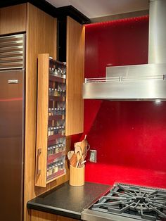 a kitchen with wooden cabinets and red backsplashing on the wall, along with a stainless steel refrigerator