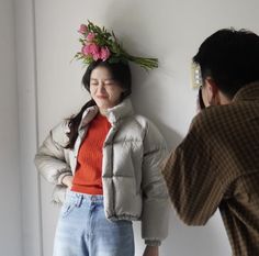 a woman standing next to a man with flowers on his head