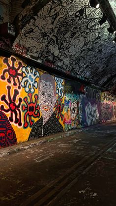 an empty parking lot with graffiti on the walls and floor, under a bridge overpass