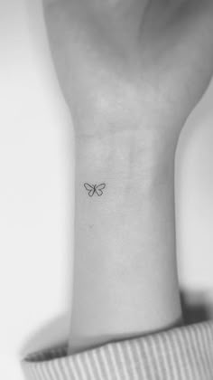 a woman's wrist with a small butterfly tattoo on the back of her arm