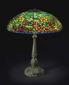 a green lamp with flowers on it and a blue light in the middle, against a black background