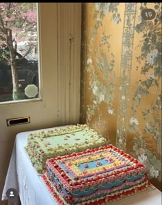 a large cake sitting on top of a table next to a wall papered window