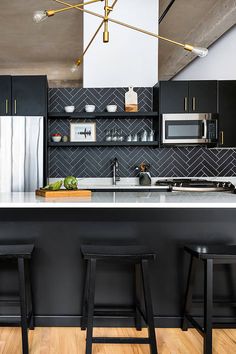 a kitchen with black cabinets and white marble counter tops, gold accents on the ceiling