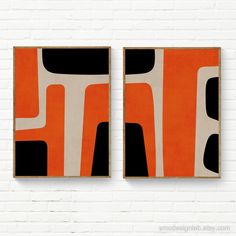 two orange and black paintings on a white brick wall