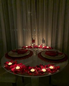 the table is set with candles and rose petals for an elegant valentine's day dinner