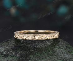 a gold wedding band sitting on top of a rock