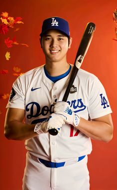 a baseball player holding a bat and wearing a white uniform with blue lettering on it