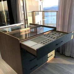 an office desk with drawers in front of a large window overlooking the water and mountains