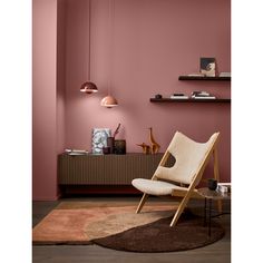 a living room with pink walls and a chair in front of a rug on the floor