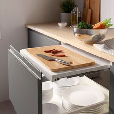 a cutting board with knives and plates on it in a kitchen next to a counter