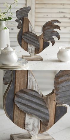 two wooden rooster sculptures sitting on top of a table next to a vase with flowers