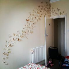 a room with a bed, chair and wall hanging butterflies on the wall above it