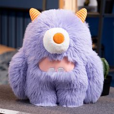 a purple stuffed animal with horns on it's head sitting on top of a table