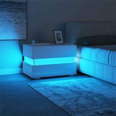 a white night stand with blue lights on it in a bedroom next to a bed