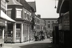 an old black and white photo of people walking down the street in front of shops