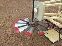 a wooden bench sitting on top of a field next to a metal windmill shaped object