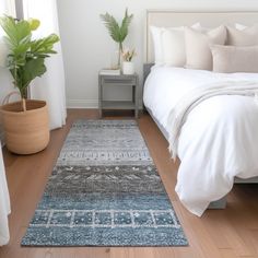 a bed with white sheets and pillows on top of it next to a potted plant