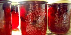 four jars filled with red liquid sitting on top of a counter