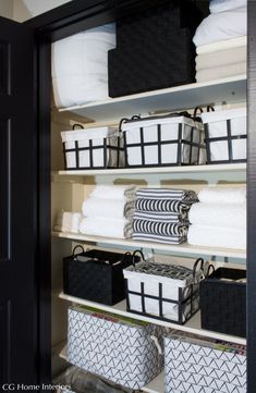 the closet is organized with black and white storage bins, baskets, and folded towels