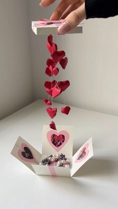 someone is placing hearts on top of a card box that has been folded in the shape of a heart