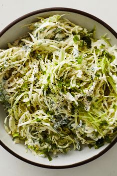 a white bowl filled with shredded broccoli on top of a table