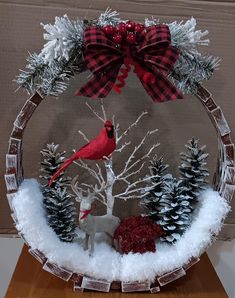 a snow globe with a red cardinal and pine cones on it, surrounded by fake trees