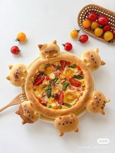 a pizza with cats on it sitting on top of a table next to fruits and vegetables