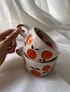 a hand is holding an orange and white cup