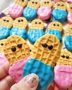 a person holding up a waffle shaped cookie with blue and pink icing on it