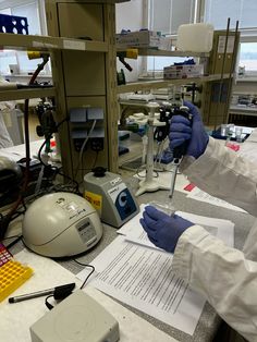 two people in lab coats and gloves working on some type of equipment with microscopes