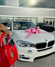 a white car with a pink bow on it's hood is parked in front of a building