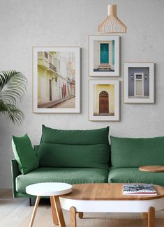 a living room with green couches and pictures on the wall above it, along with a coffee table