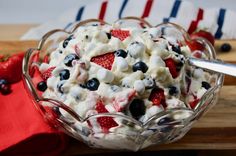 a bowl filled with fruit on top of a wooden cutting board next to a red white and blue napkin