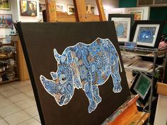 the rhinoceros are painted on canvases in an art shop with other items