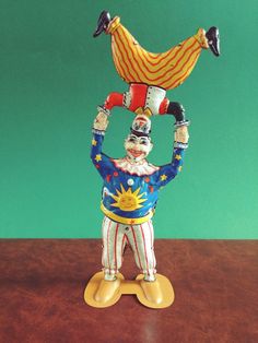 a statue of a clown holding a bird on top of his head while standing on a table