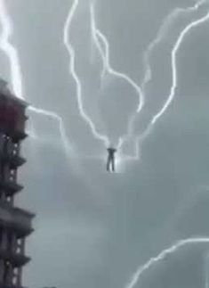 a man standing on top of a tall building under lightning