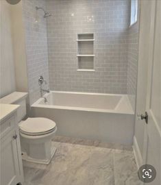 a white toilet sitting next to a bath tub in a bathroom under a chandelier