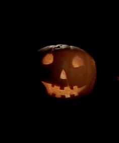 two jack o lantern pumpkins lit up in the dark