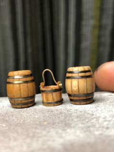 three wooden barrels sitting on top of a table next to a person's finger