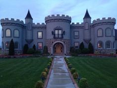 a large castle like building sitting on top of a lush green field next to a sidewalk