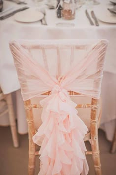 a chair with a pink ruffled sash on it's back and the seat cover is down