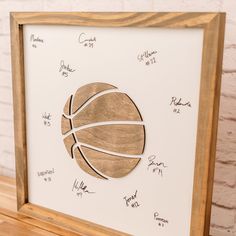 a framed basketball is on display in front of a white brick wall and wooden shelf