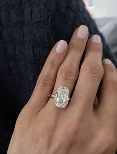 a woman's hand with a diamond ring on her left hand and the other hand holding an engagement ring