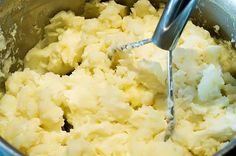 a mixing bowl filled with mashed potatoes and a whisk