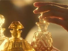 a person holding an object in their hand next to other items on a table with gold trimmings