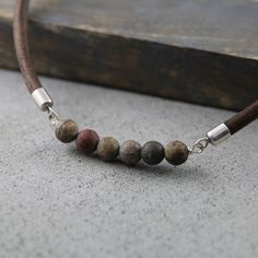 This men's necklace features rugged jasper stones paired with a brown leather cord and oxidized sterling silver accents, creating a bold yet natural look. The earthy tones of the jasper add a unique charm, while the durable leather ensures lasting comfort. Perfect for everyday wear or as a thoughtful gift for someone special, this necklace embodies both style and strength. Ideal for those who appreciate handmade, rustic jewelry with a masculine edge. Details: Length : The drop down menu on the r Mens Choker, Masculine Jewelry, Mens Leather Necklace, Leather Anniversary Gift, Brown Necklace, Jasper Necklace, Man Gift, Rustic Jewelry, Valentines Gifts For Him