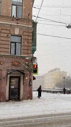 a person walking down a snowy street in front of a building