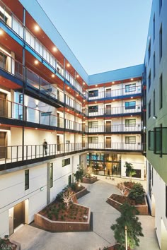 an apartment building with many balconies and plants in the courtyard at night time